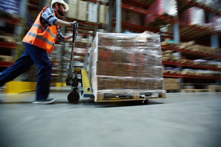 Worker pushing a cart full of boxes in a warehouse.
