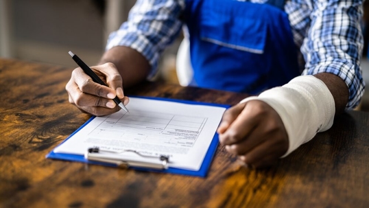 Injured worker wearing an arm cast writing on a form.