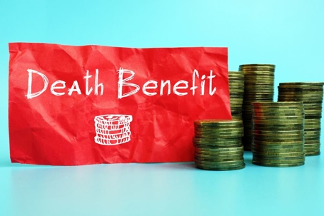 Crumpled red-colored paper along with stacks of coins, with the words etched in white, "Death Benefit".